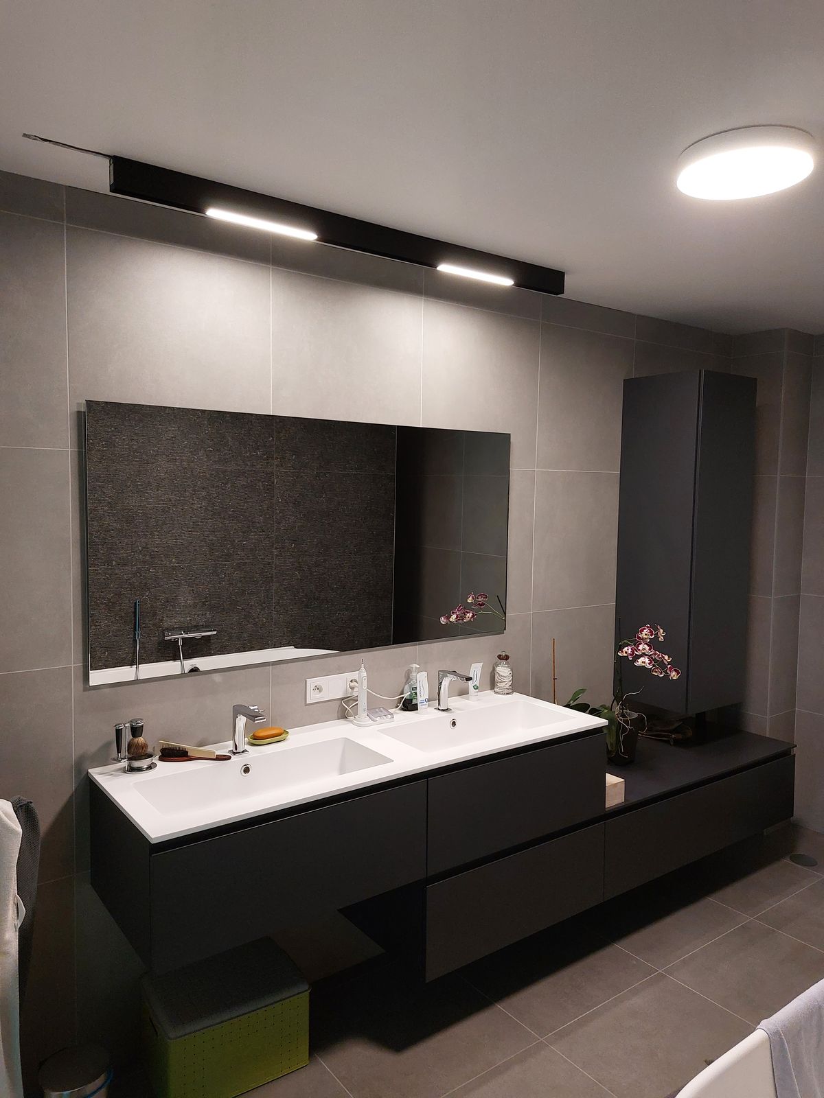 Badkamer met dubbele lavabo en lijnverlichting boven de spiegel